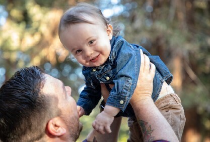 A dad holding a baby up in the air