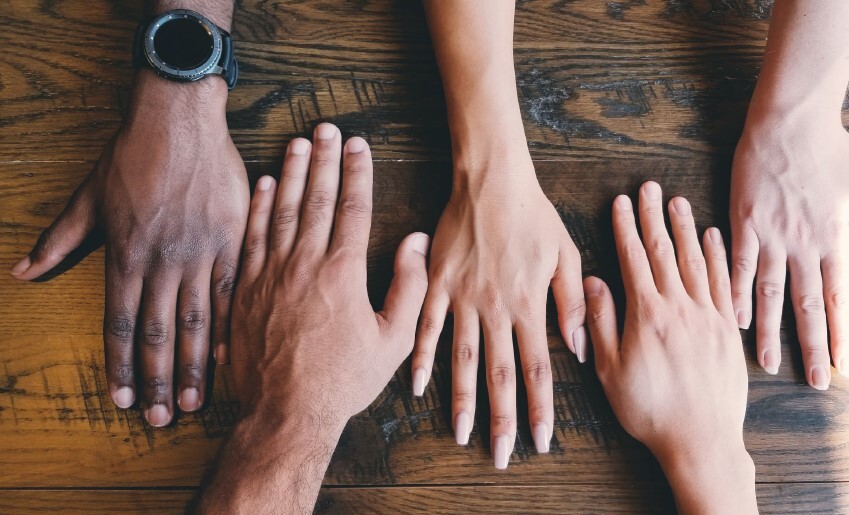 Two sets of hands laying on a table.