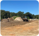 A cleared lot with heavy equipment tracks in the dirt. Leveling and elevation control has begun. 