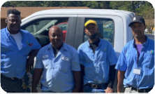 Four men stand together; all are wearing the same shirt.