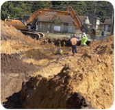 A large tractor is digging into the ground to do drain line installation.