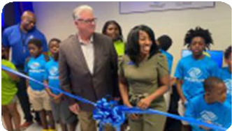 Two adults and several children stand behind a ribbon during the computer lab unveiling. 