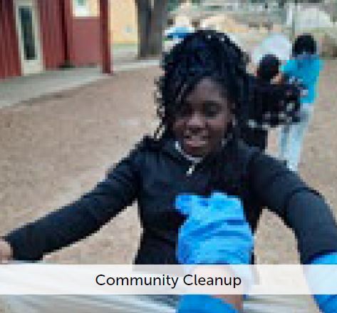 Community Cleanup - A young girl holding open a trash bag for someone to throw away trash.