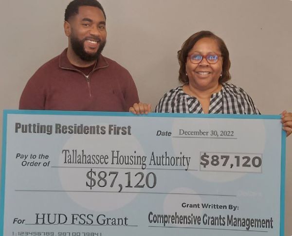 A man and woman holding a giant check for the Tallahassee Housing Authority in the amount of $87,120.