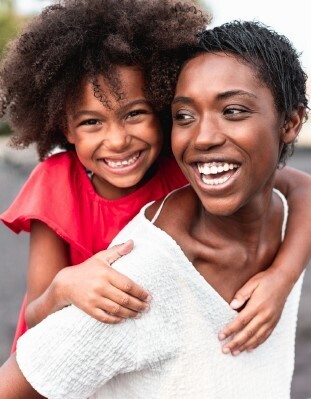 A daughter sitting on a mothers shoulders.