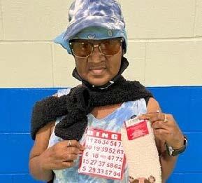 Woman wearing sunglasses, holding Bingo prizes.