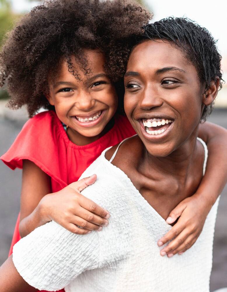 Mother with child on her shoulders, both are smiling.