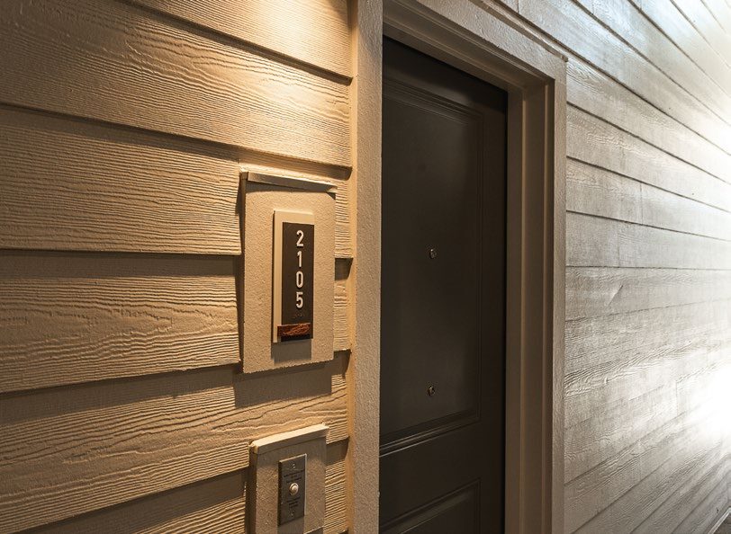 An apartment doorway in a hallway with house number and doorbell. 