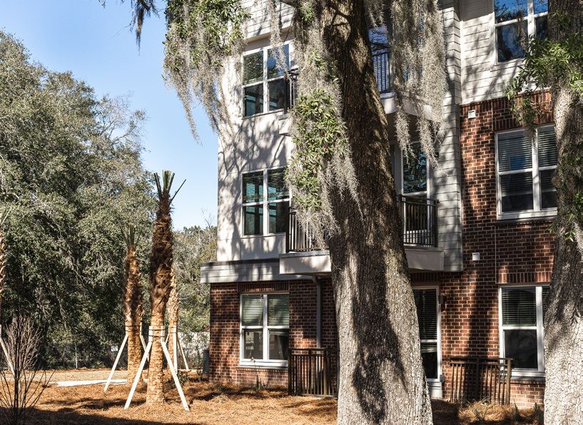 Corner of the apartment complex outside shaded with palm trees. 