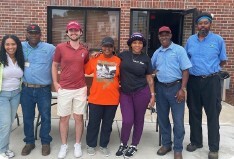 A group of seven people standing and smiling after receiving goods.