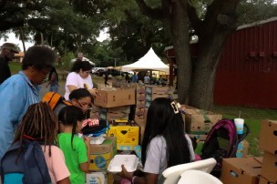 People outside looking in boxes of school supplies.