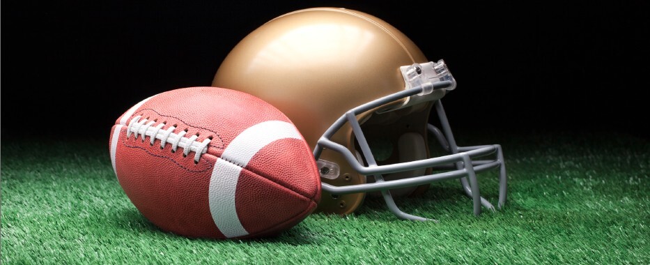A football and helmet on turf. 