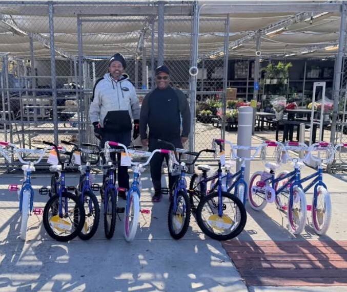 Two people standing behind a line of 10 bicycles.