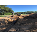 A tractor works on installing drainage pipes into the large holes in the ground. 