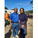 A gentleman and woman stand smiling with their arms around one another. 