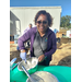 A woman looks up and smiles as she is whisking pancake batter in two big bowls. 