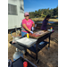 A staff member smiles brightly as she cuts up sausage to fry on a flat top grill. 