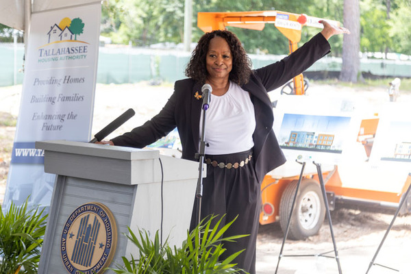 A woman gesturing behind a podium.