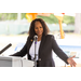 A woman gestures with her hands while talking to a crowd.