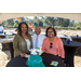 Three people at a table under a canopy.