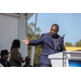 Man points to other speakers on stage. 