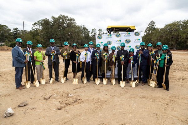 Team with shovels and hard hats pose for photo. 