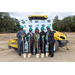 Five people stand before equipment with shovels and hard hats. 