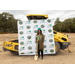 Woman stands before a backdrop with shovel and hard hat. 