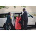 Two individuals helping Hud Secretary Marcia Fudge out of a white SUV.